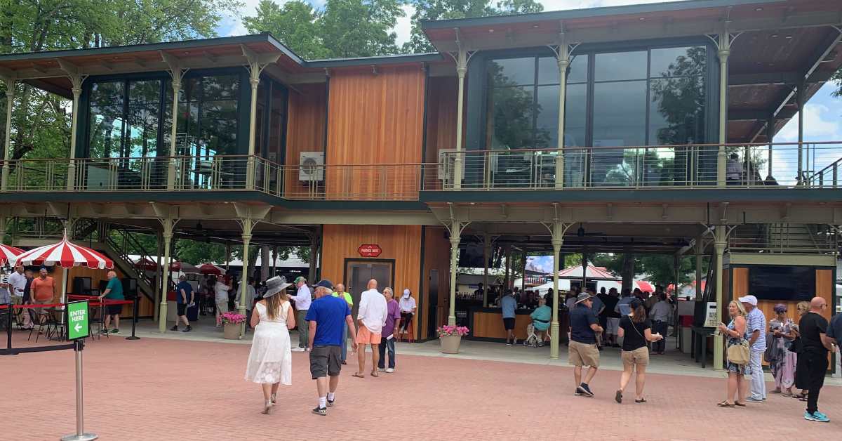 people walking toward a two-story suite section at a horse racetrack