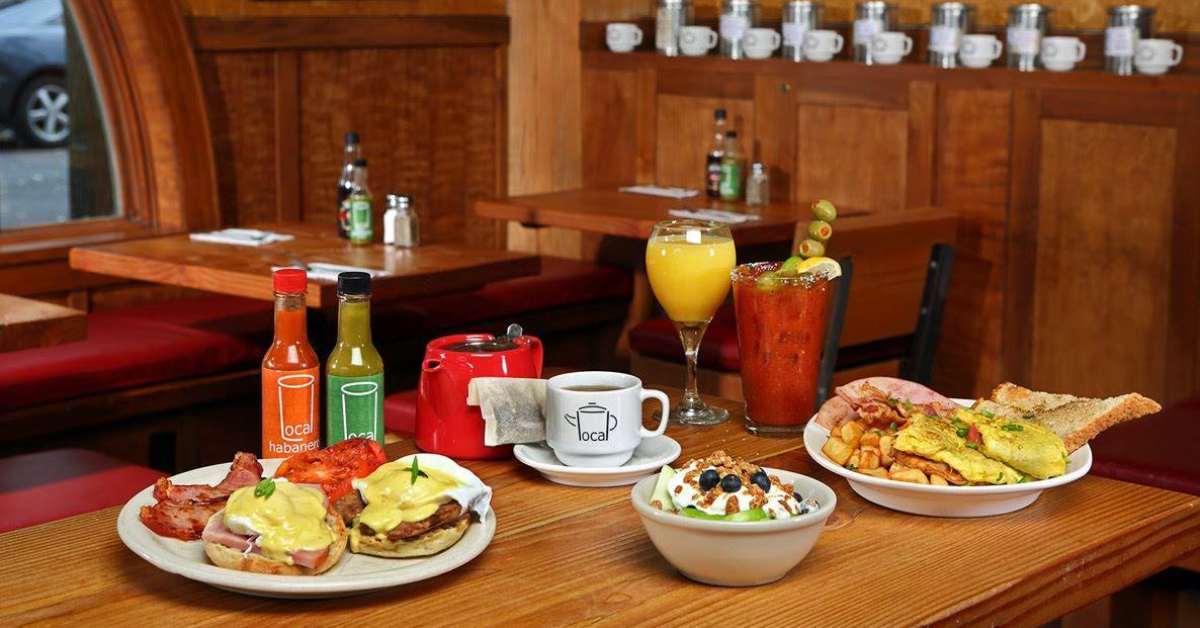 restaurant table with plates of brunch food and tea, coffee, and a Bloody Mary