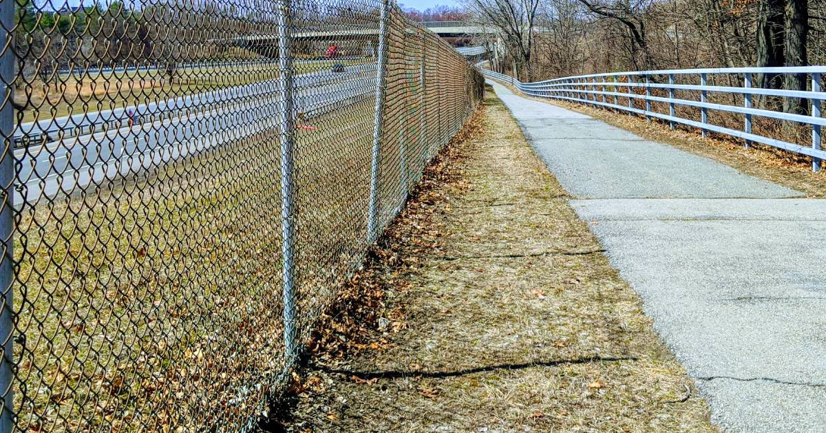 walking path by a highway with fences