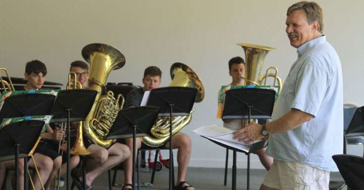 a music instructor in front of a small brass band of kids