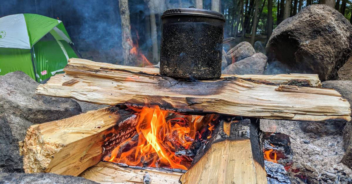 pan on fire, tent nearby in woods