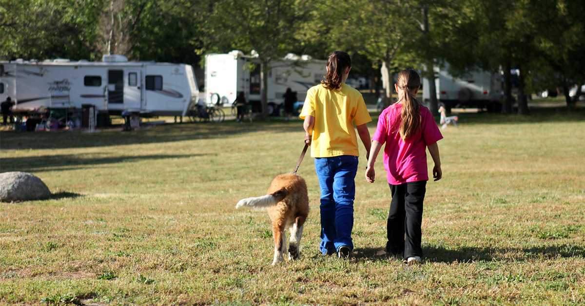 two girls walking a dog at a campground
