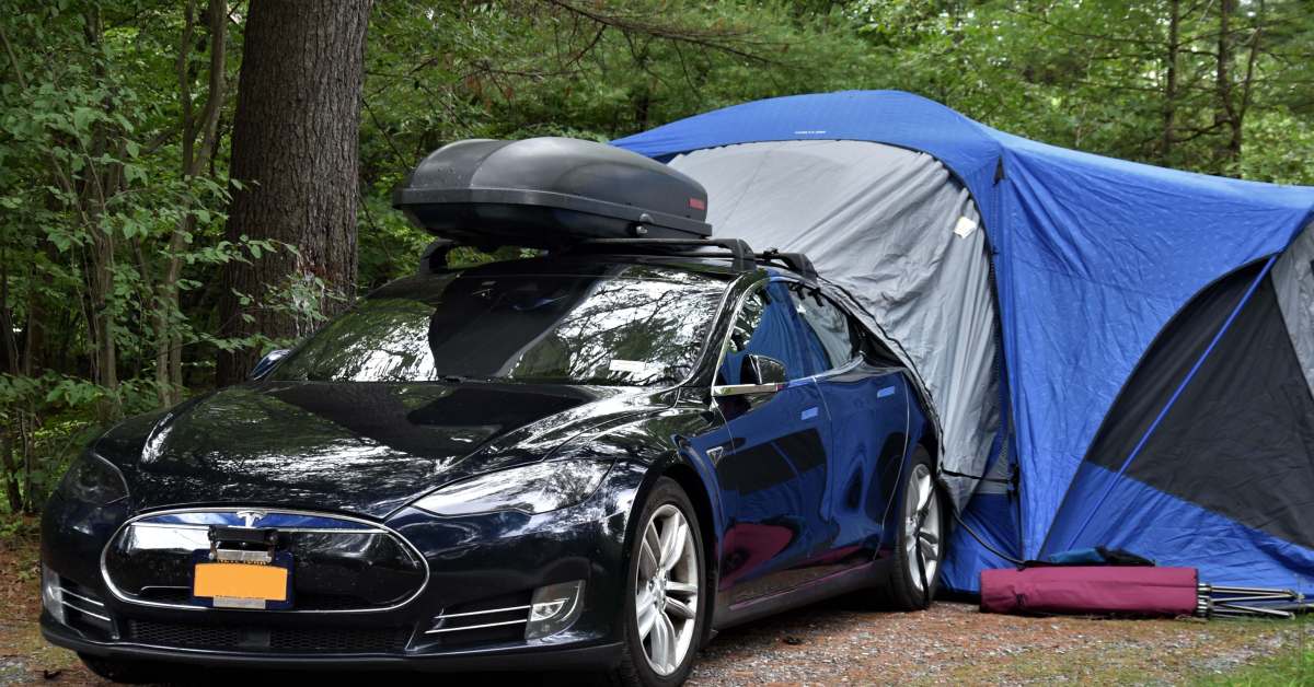 car in woods with tent attached to back