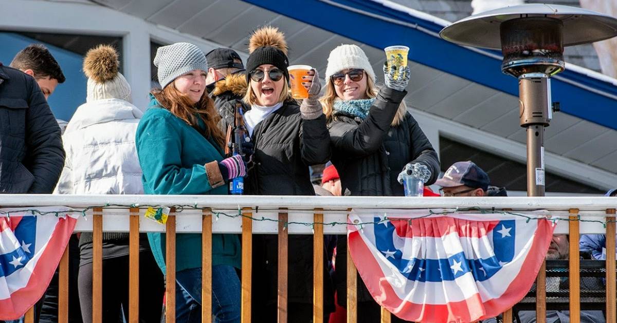 three women standing by people on a restaurant deck in winter