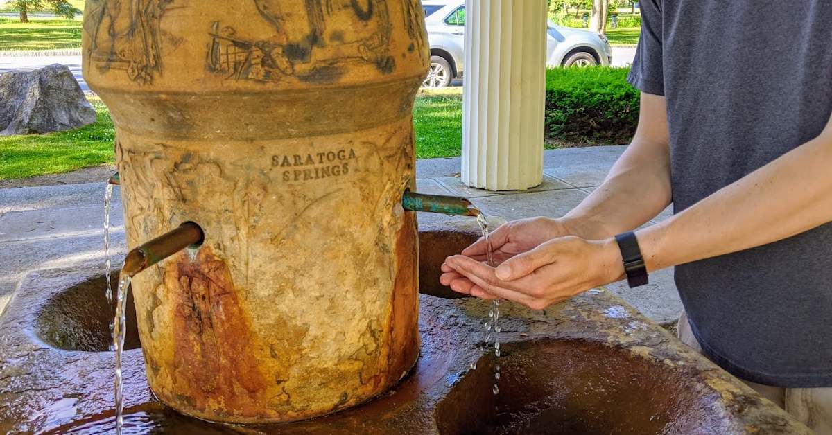 hands cupping water at mineral spring