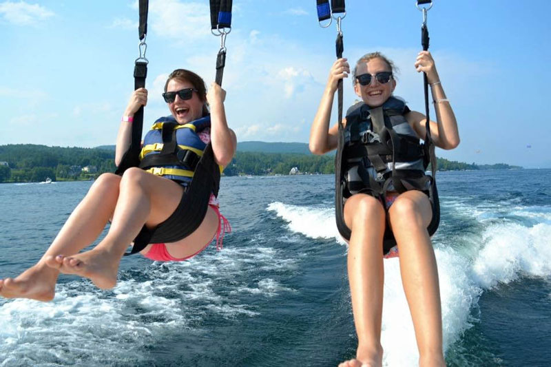 two women parasailing above a lake