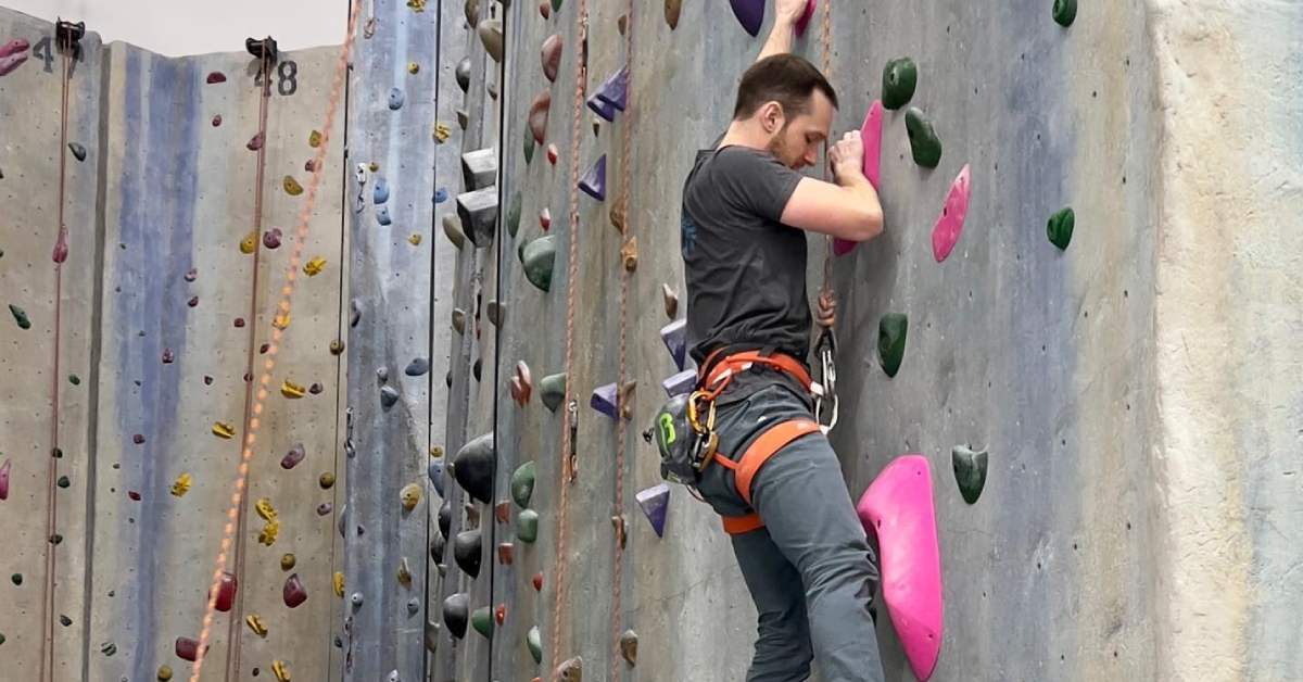 man rock climbs on indoor rock climbing wall