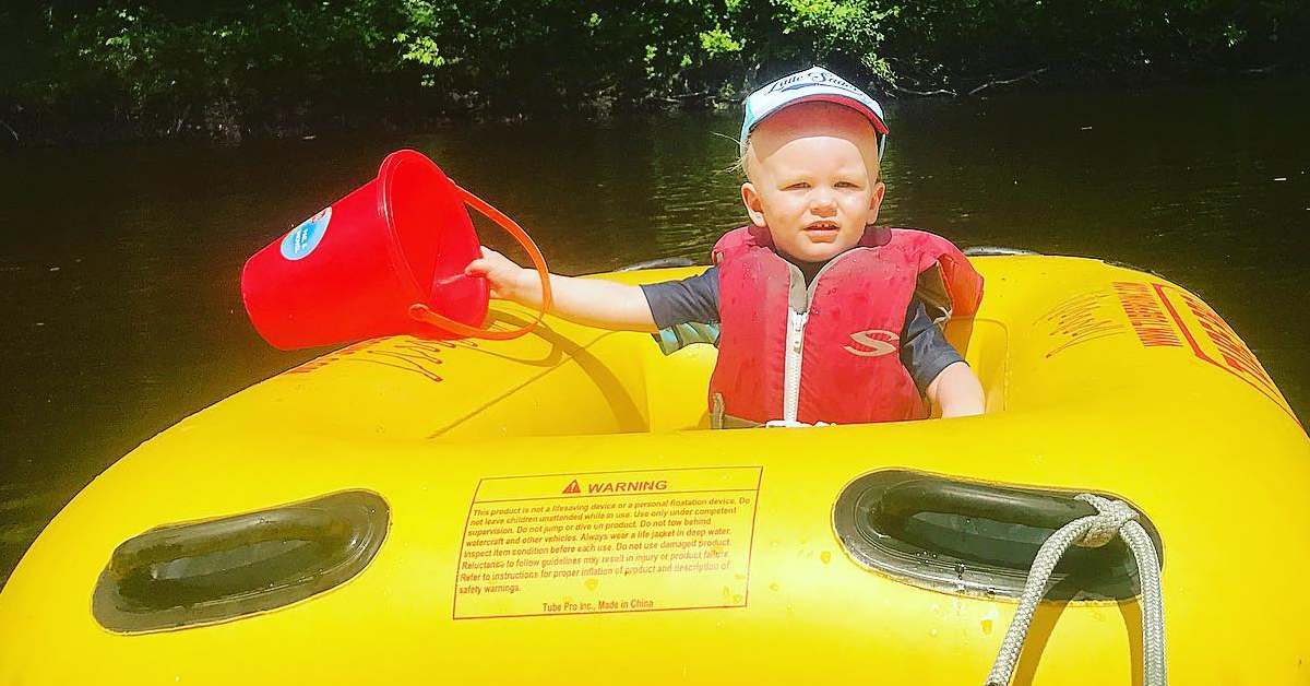 toddler in yellow raft holds a red bucket