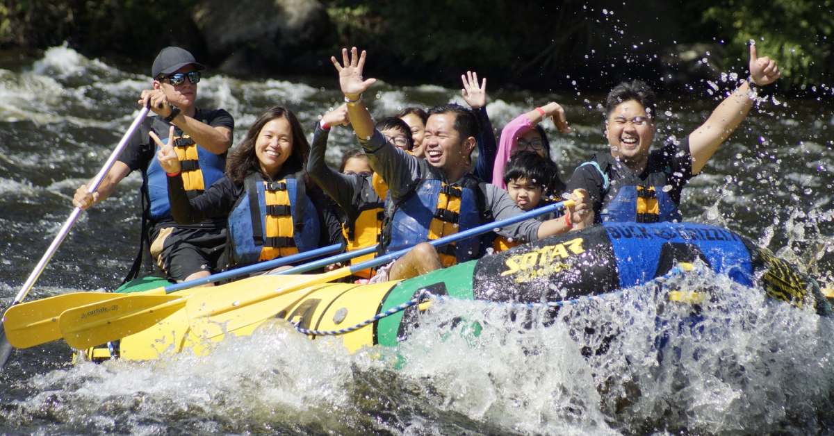 group whitewater rafting and waving and smiling