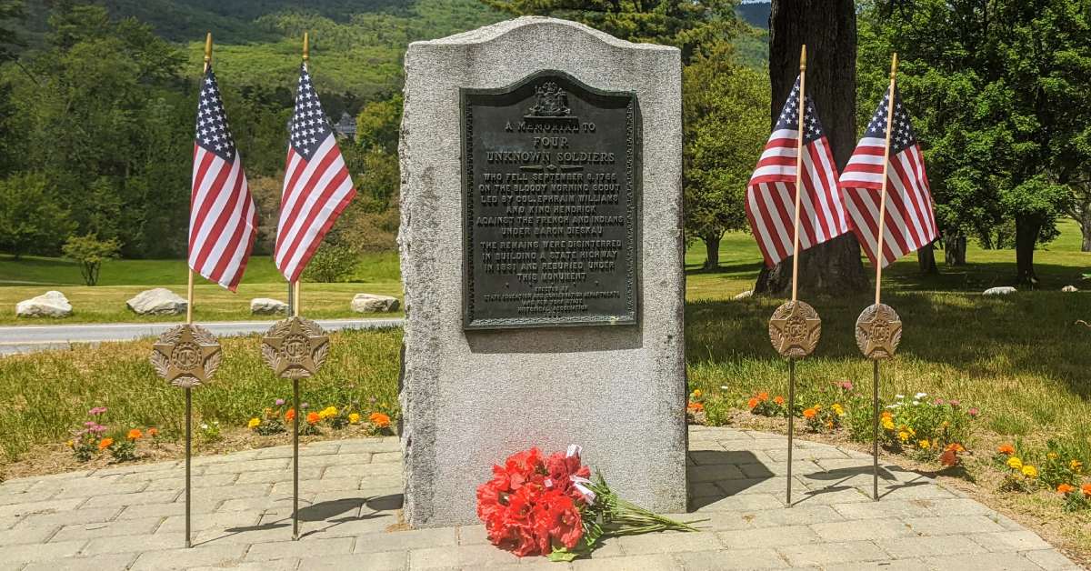 four soldiers memorial surrounded by american flags