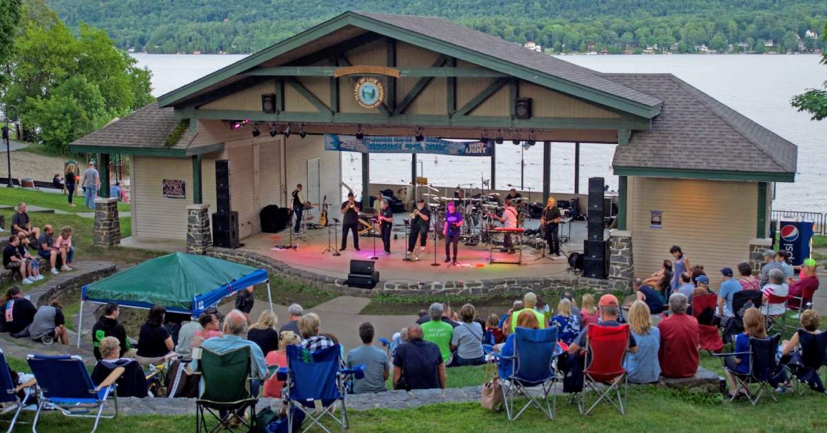 band performers at amphitheater in front of lake