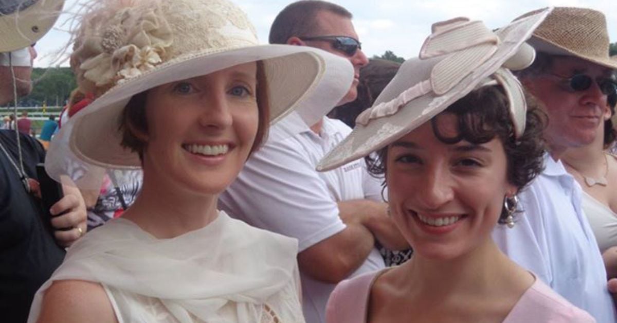 two women wearing fancy hats at a horse racetrack