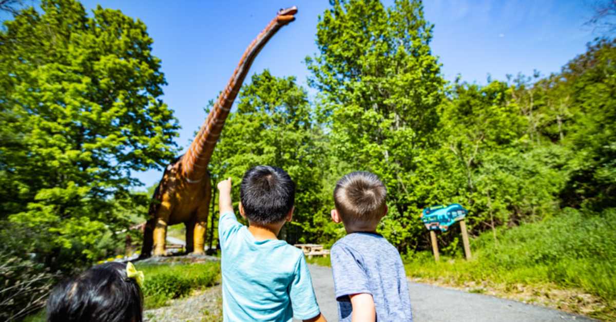 two kids looking at a dinosaur attraction