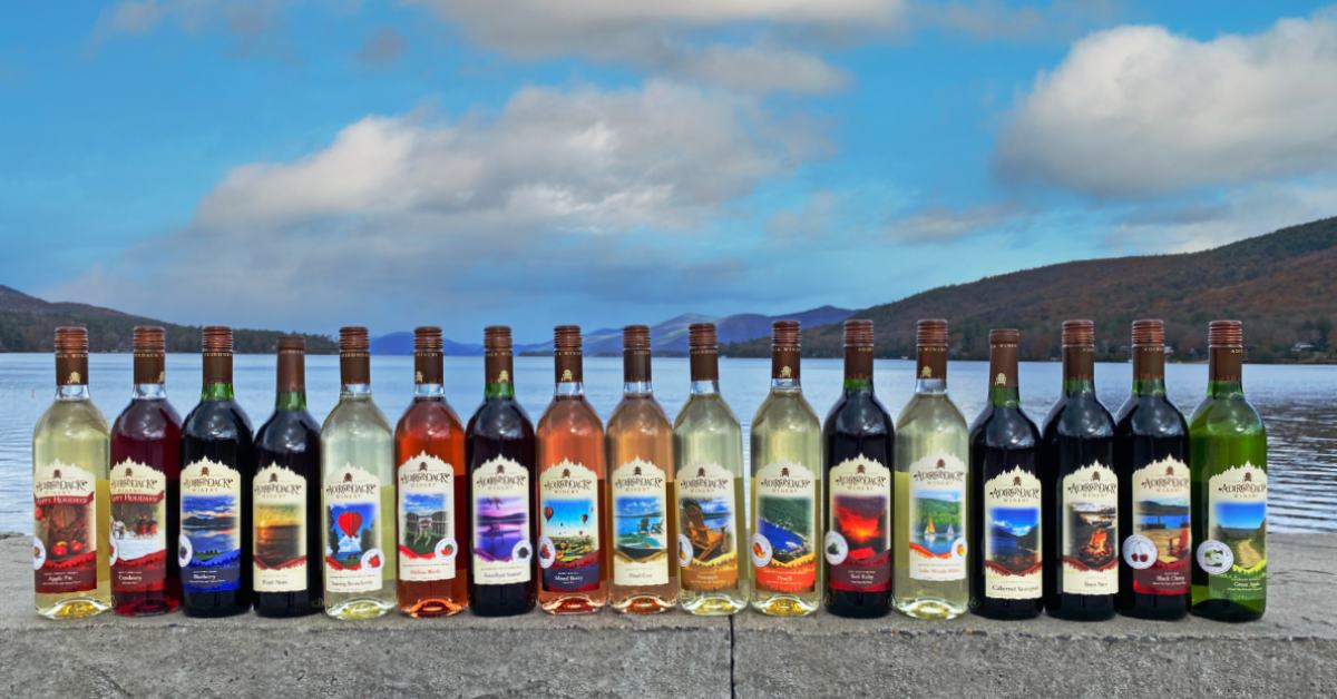 wine bottles from adirondack winery lined up in front of a lake