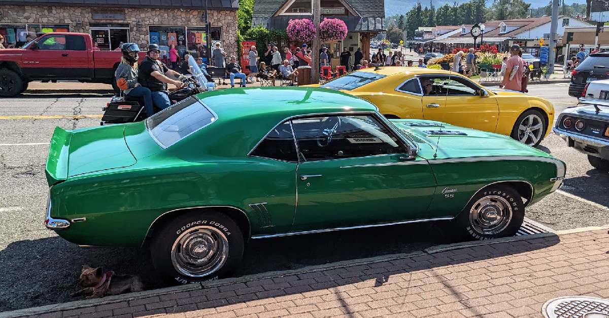 old classic green car at curb, crowd in lake george behind