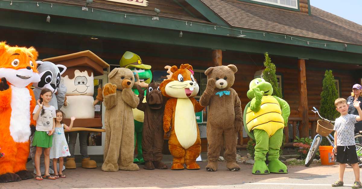 costumed characters line up in front of lodge, pose with a couple kids