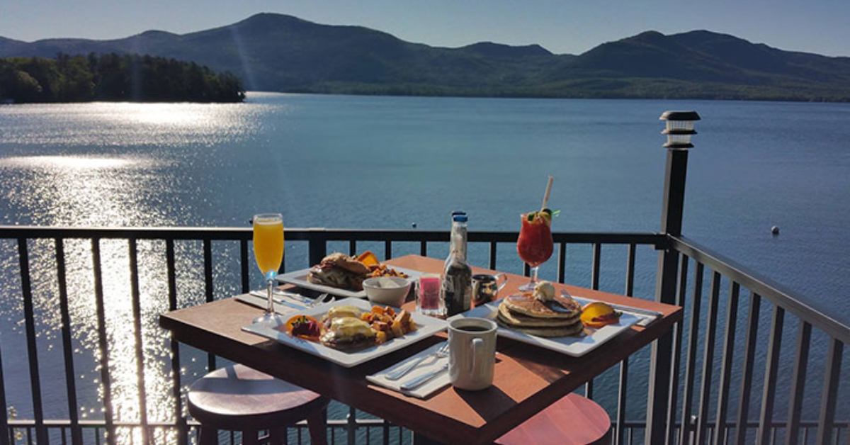 food and drinks on a patio table overlooking a lake