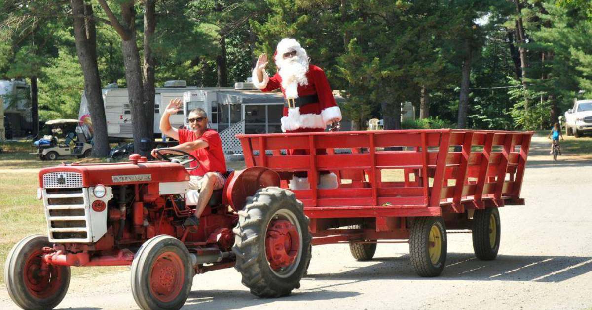 santa being escorted on a wagon hauled by a tractor