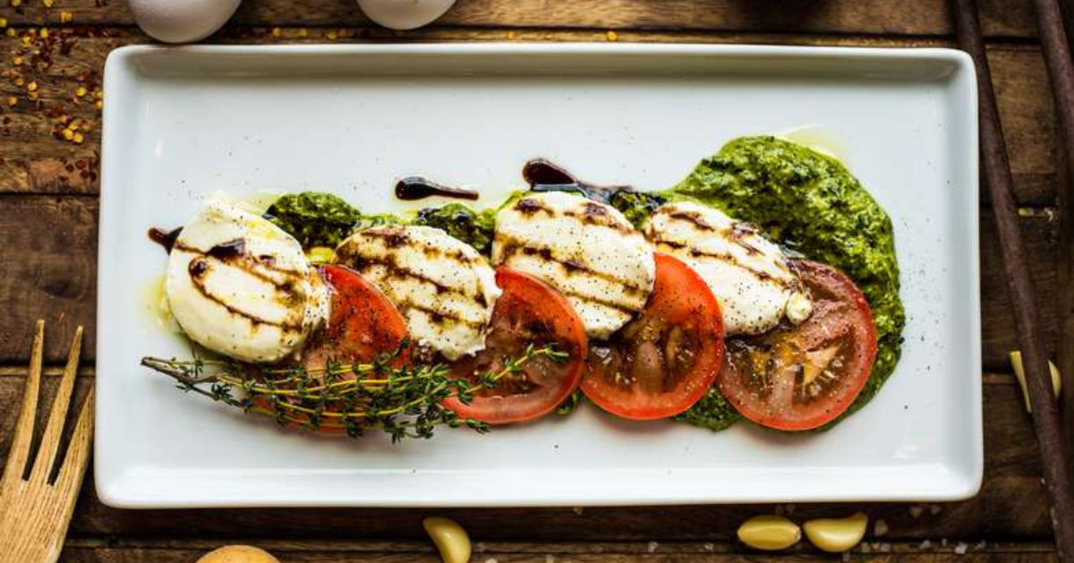 plate with mozzarella, tomatoes, and pesto on it