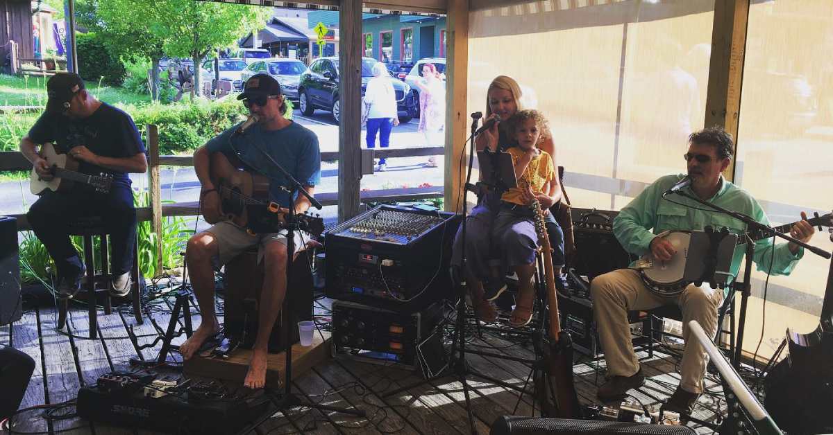 three men and a woman playing music at a restaurant on a patio