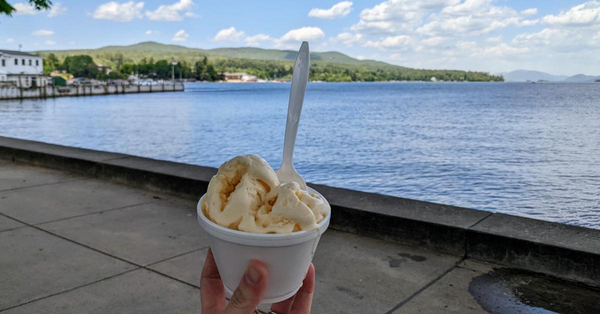 person holding cup of ice cream next to lake george