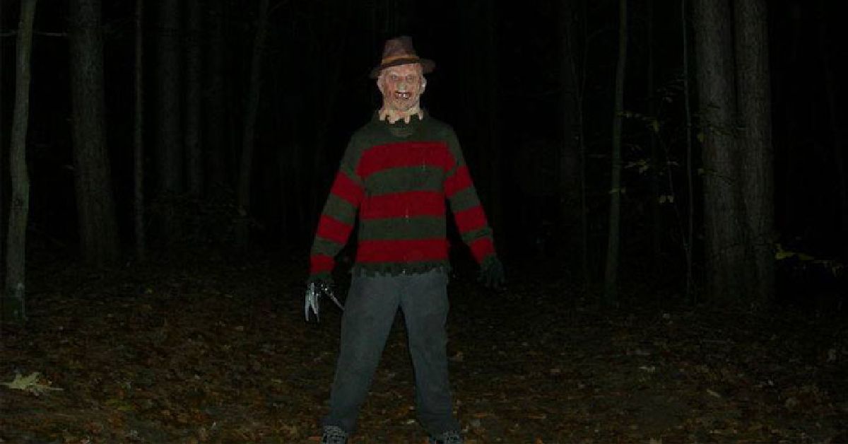 scarecrow guy with scissors for hands in the woods