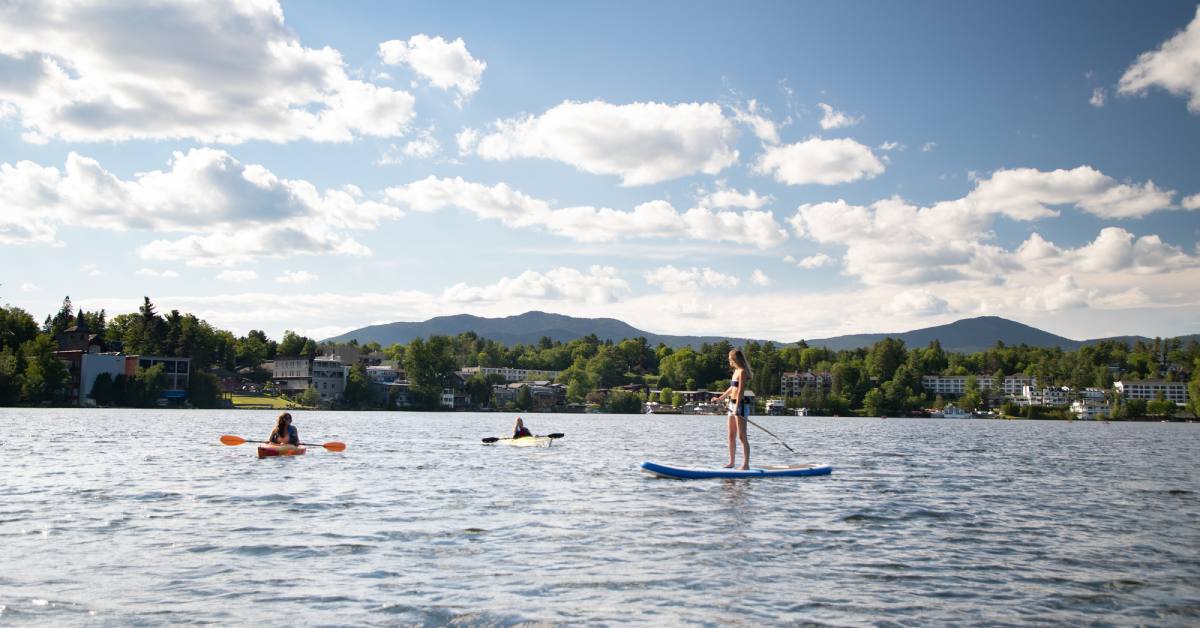 people in kayaks and on a stand up paddleboard in the water