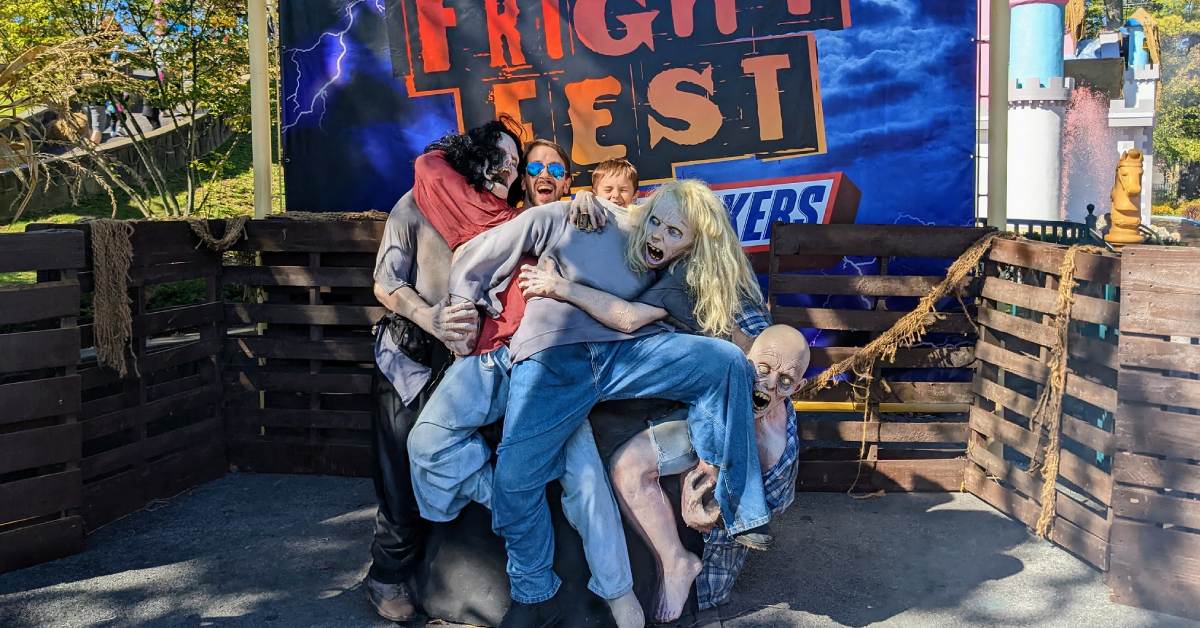 dad and kid pose at fright fest photo op with pretend zombies