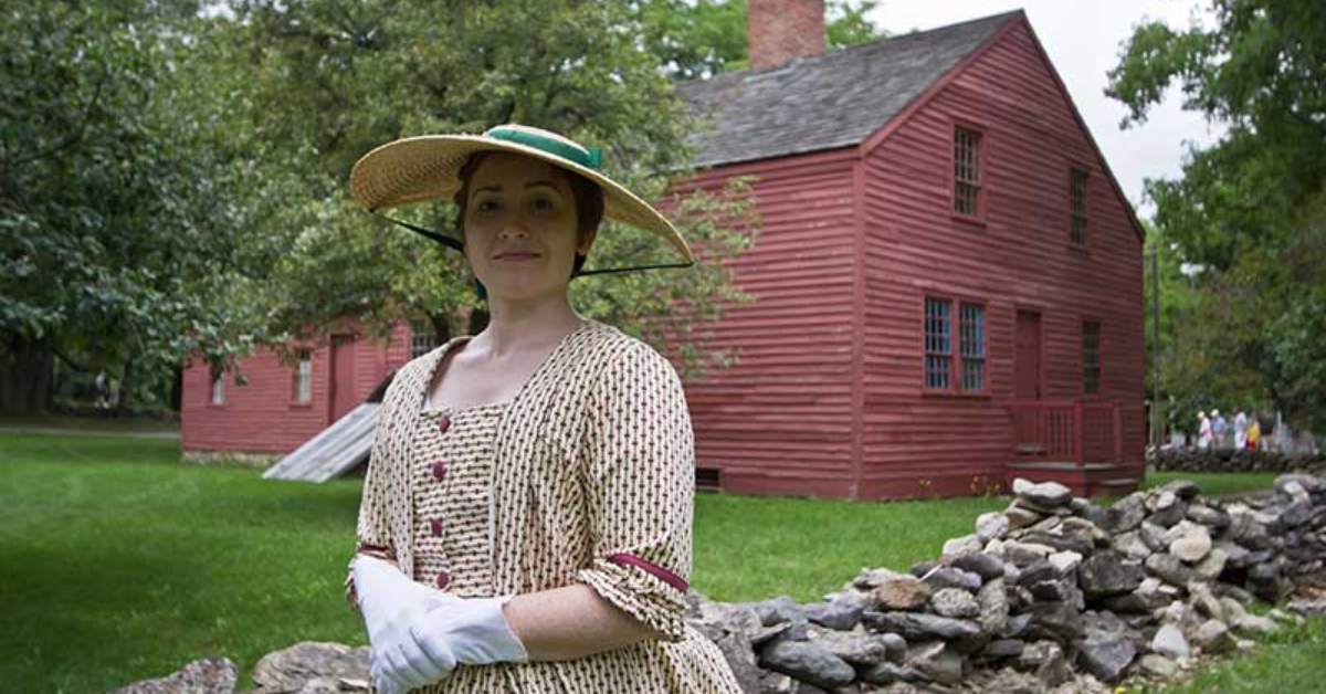 woman in a dress and hat standing in front of a red building