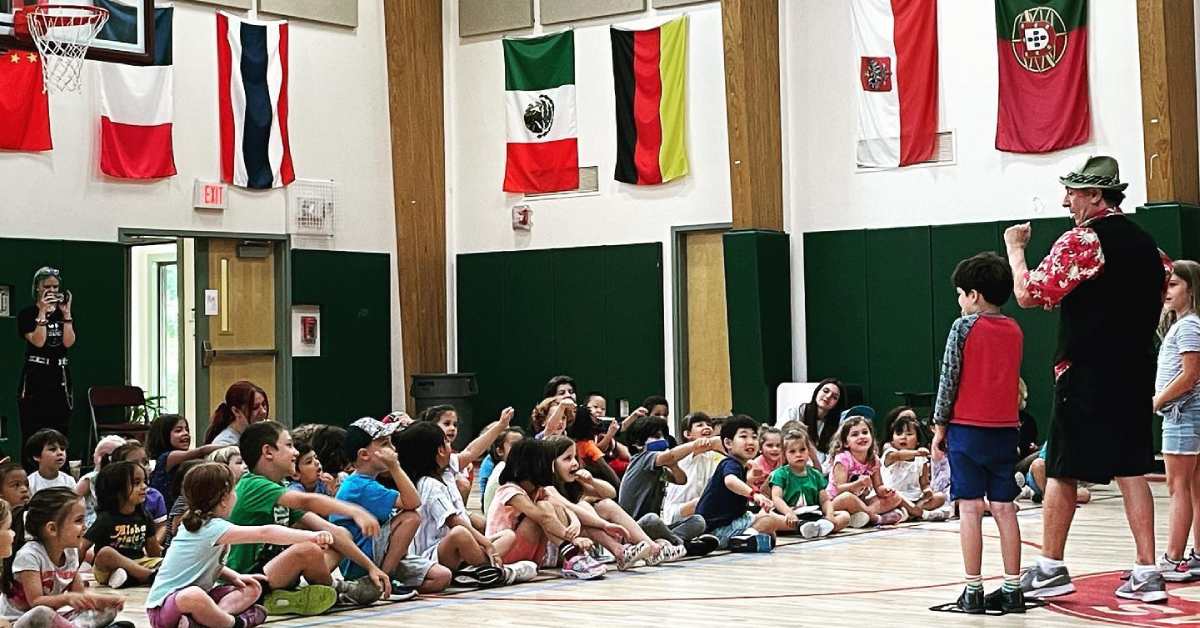 group of kids sitting in a gym in a summer camp