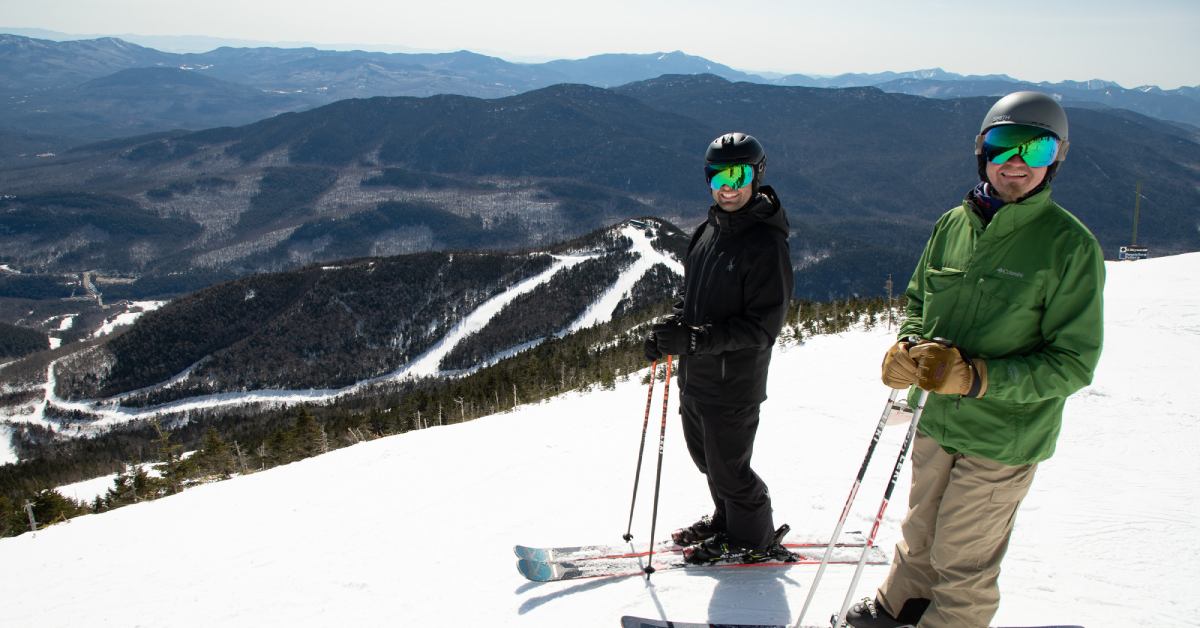 two people on skis at the top of a mountain
