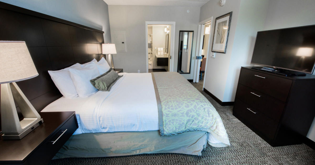 a hotel room with a large bed and dresser with TV