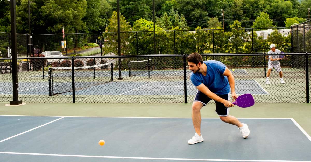 man plays pickleball on outdoor court