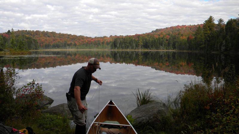Man loading a canoe into a pond near Olmstedville NY