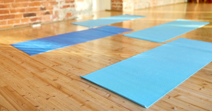four yoga mats on a wooden floor