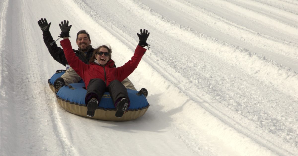 two people snow tubing down a hill in blue tubes