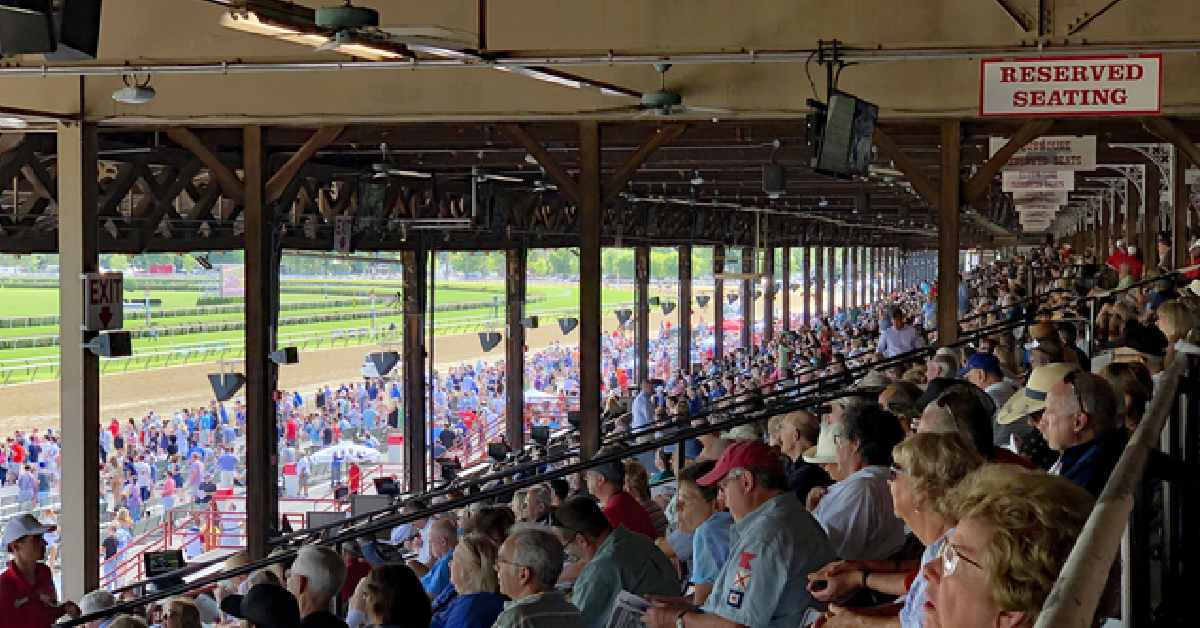 Crowded bleachers overlooking a horse racing track.