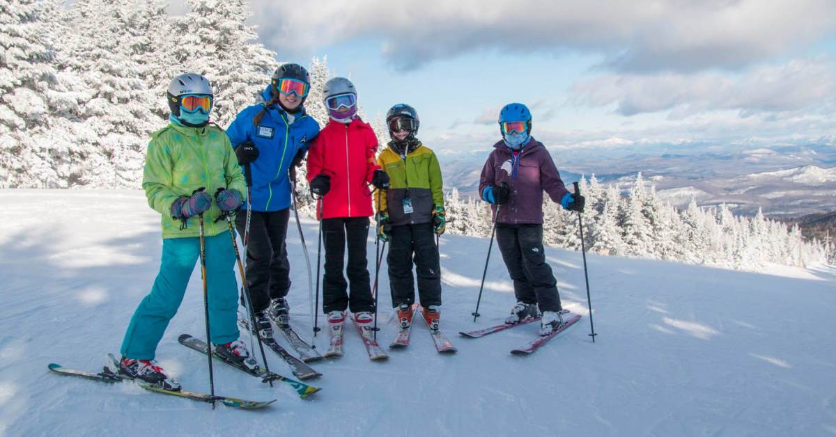 a family of five wearing skis on a mountain