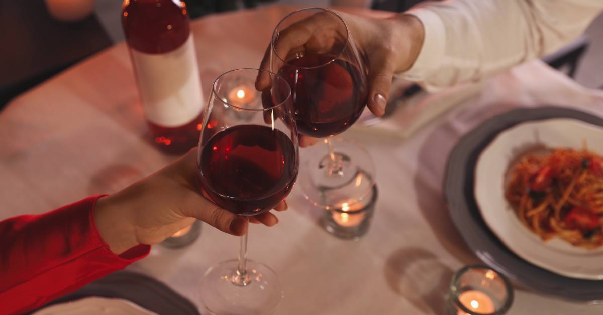 two glasses of red wine cheers over table