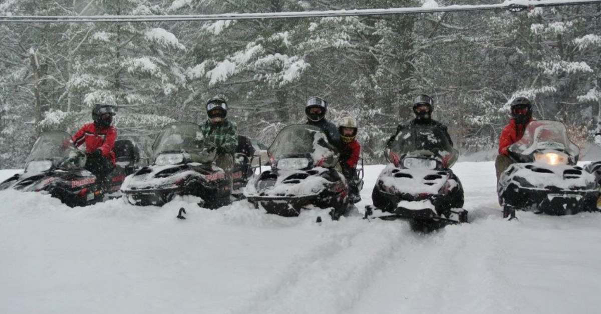 a lineup of people on snowmobiles