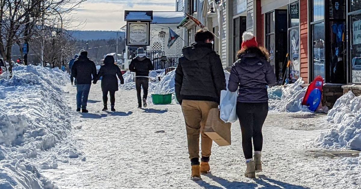 people walk in lake george village in winter with shopping bags