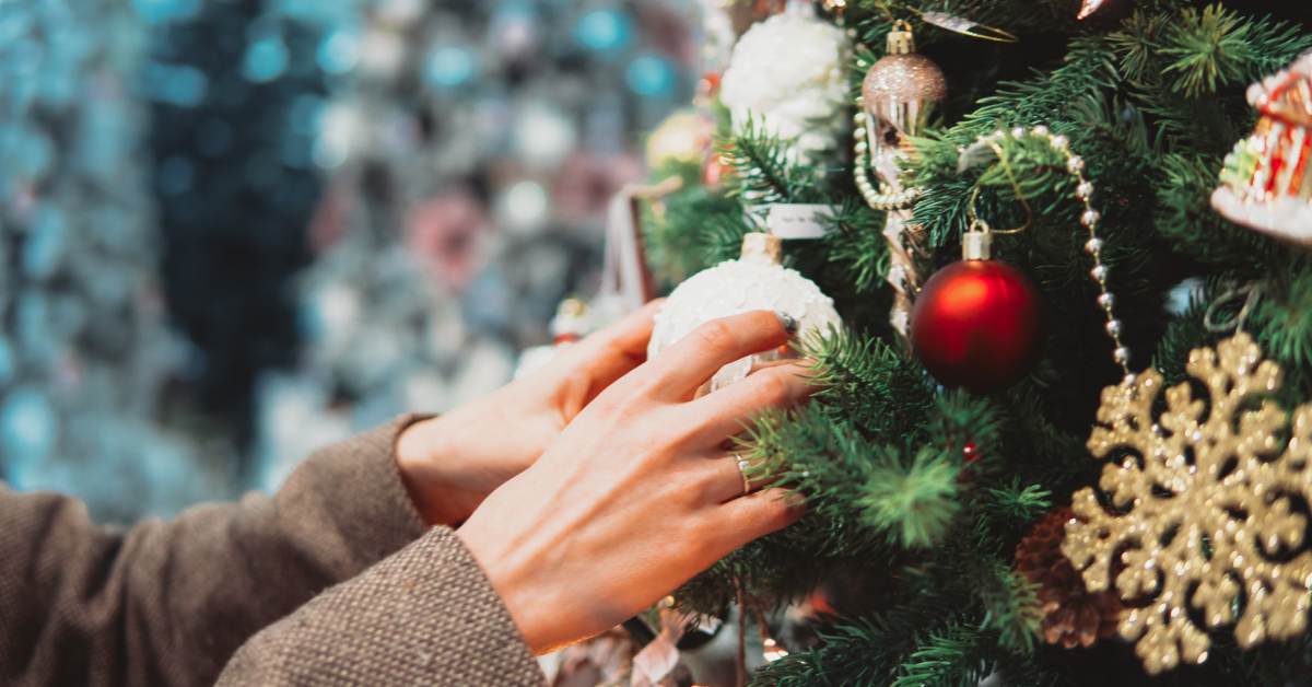 a person adding a decorating to a Christmas tree