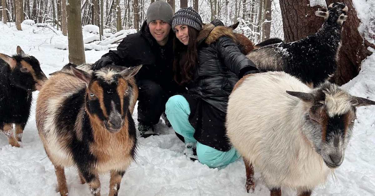 man and woman with goats in snowy woods