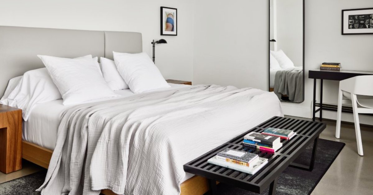 a hotel bedroom with bed, desk, and bench