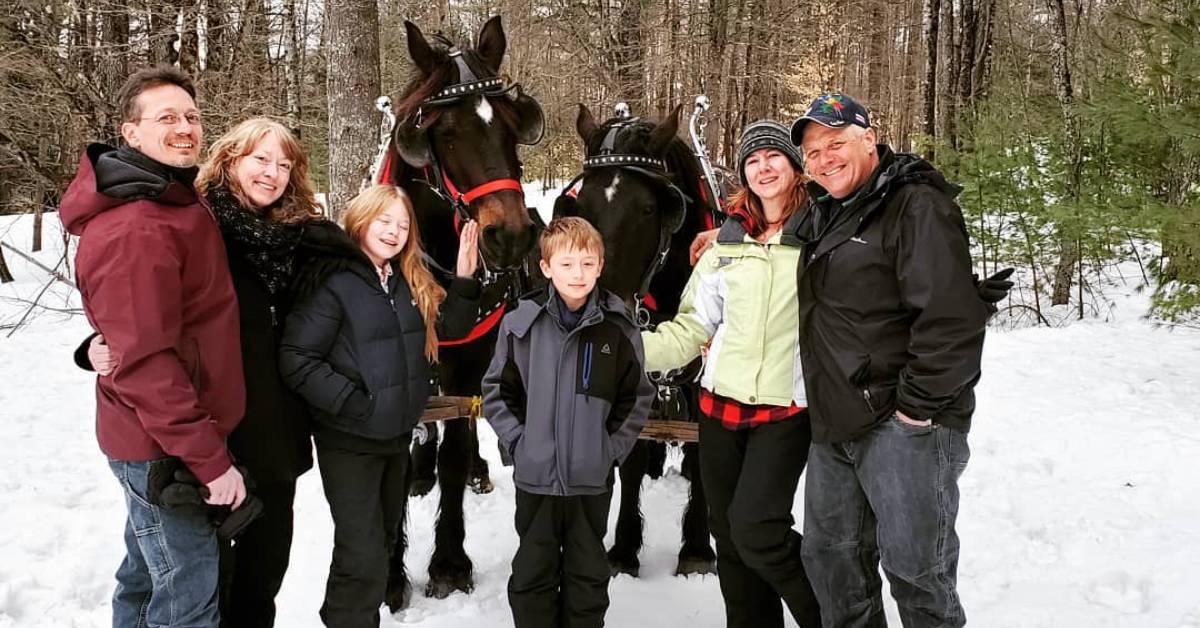 family poses by two horses