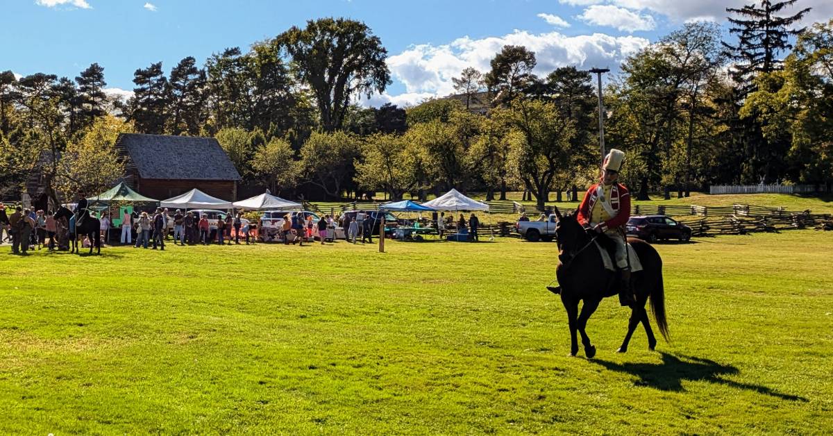 man rides horse near people and vendors at fort ticonderoga