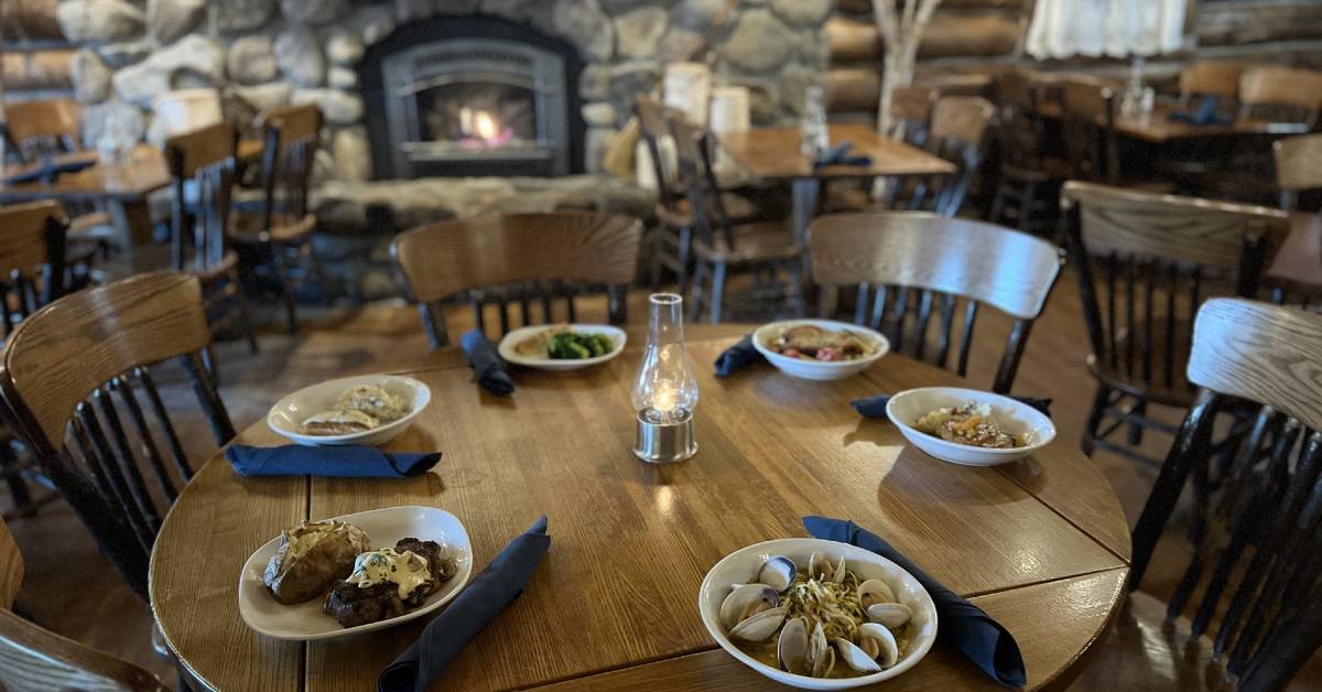 dining table set and fire in fireplace in log jam