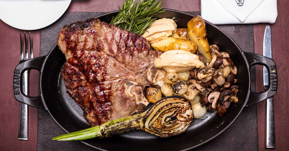 black dish with steak, mushrooms, and veggies