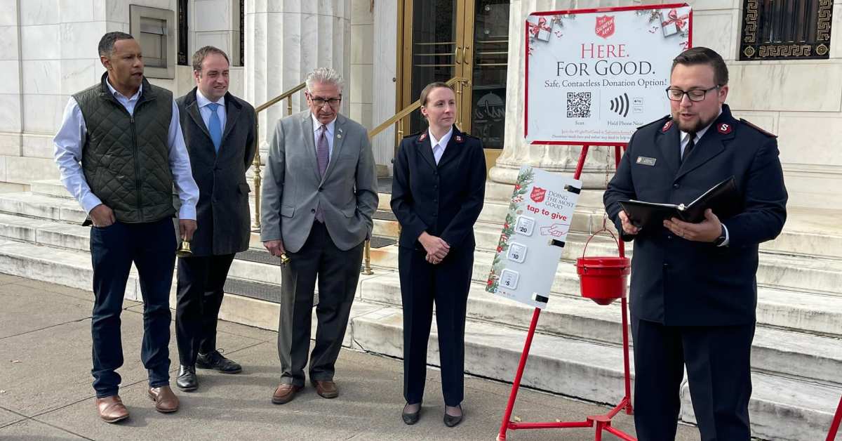 people standing by a red kettle for the salvation army