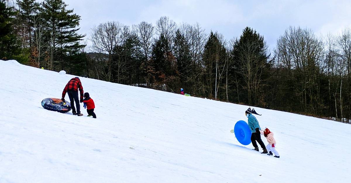 people going up hill with snow tubes